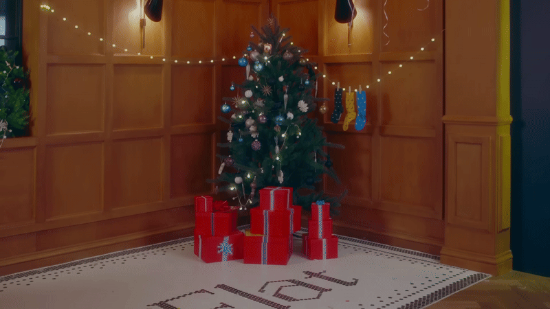 A gif of presents appearing in front of a Christmas tree.